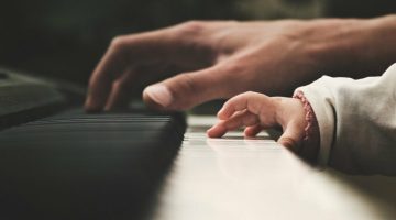 Adult and kid hands playing a keyboard